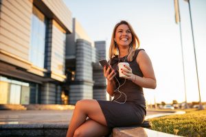 млада жена държи кафе и използва интернет за да говори по телефона